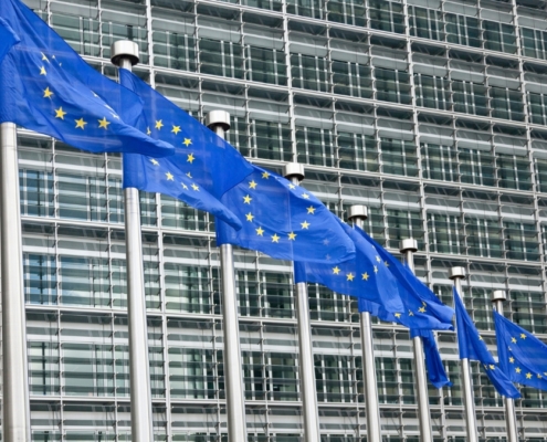 flagi unii europejskiej przed gmachem parlementu europejskiego